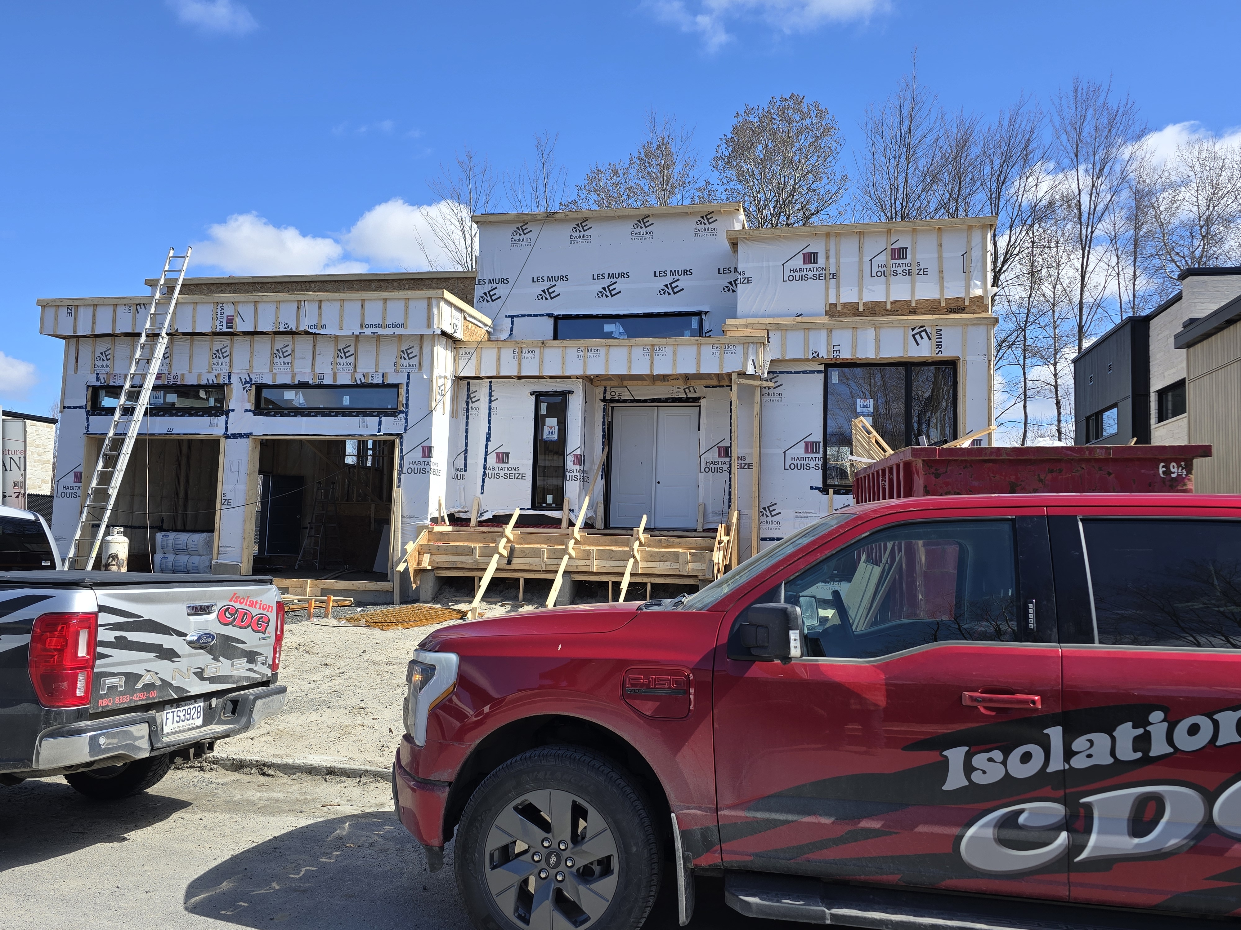 Maison sur mesure en construction avec véhicules Isolation CDG sur le chantier