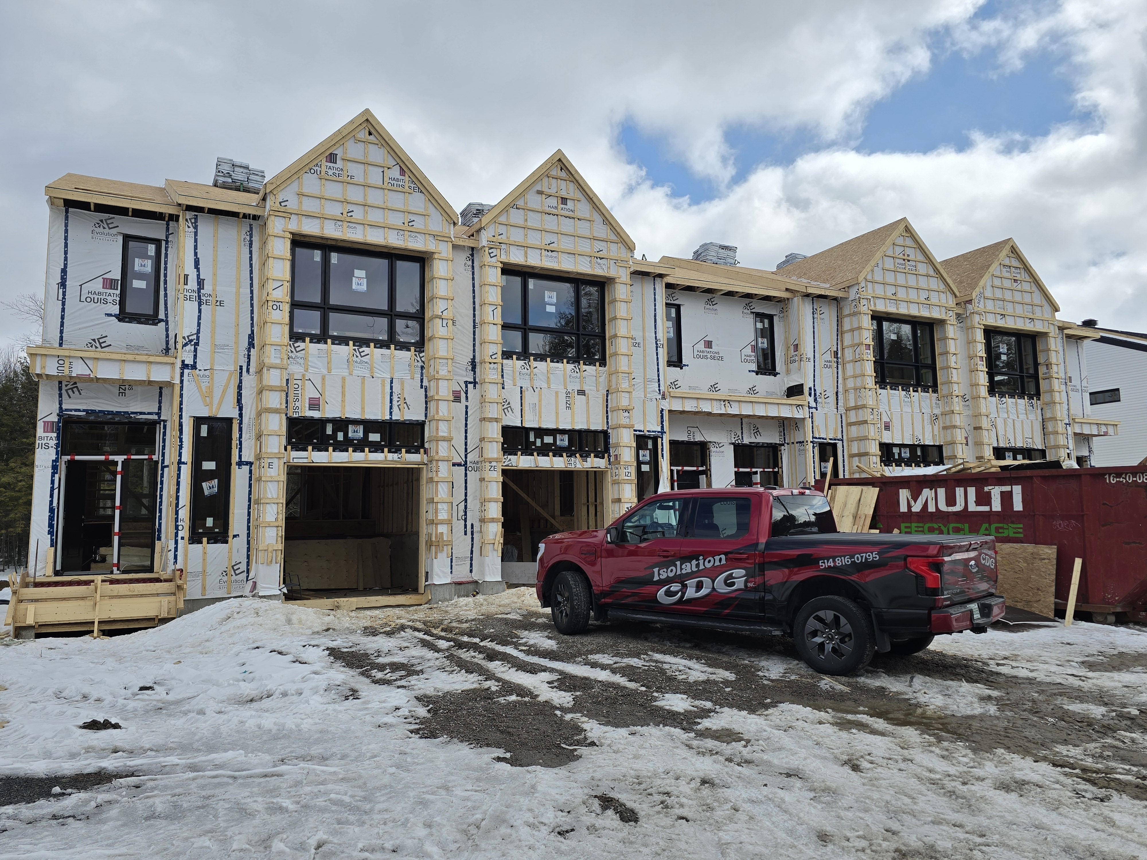 Rangée de maisons en construction avec pare-air et camion CDG sur le chantier